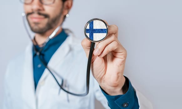 Doctor holding stethoscope with Finland flag. Finland Health and Care Concept, Finland flag on stethoscope