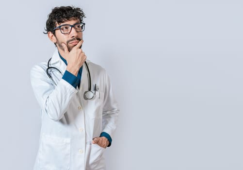 Doctor thinking with hand on chin. Young doctor thinking and looking up isolated, Pensive doctor man looking up isolated