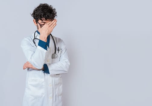 Exhausted doctor with hand on forehead isolated. Tired doctor with hand on forehead
