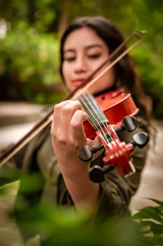 Lifestyle of girl with her violin playing a melody outdoors, Concept of smiling female violinist. Latin girl playing the violin outdoors. Portrait of a latin girl playing the violin outdoors