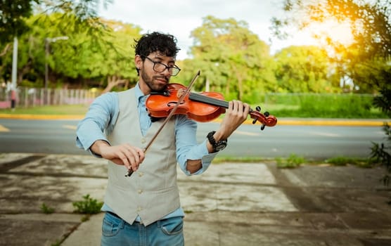 Violinist artist playing a melody outdoors, Portrait of man playing violin outdoor. Close up of violinist man playing in the street. Image of a person playing the violin outdoors