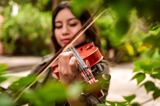 Girl with her violin playing a melody outdoors, Concept of smiling female violinist. Attractive girl playing the violin outdoors. Portrait of a girl playing the violin outdoors