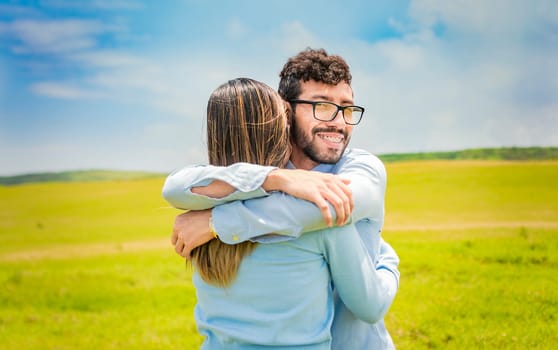 A man hugging his woman in a beautiful field, Close up of a happy couple hugging in the field, a young couple in love hugging in the green field