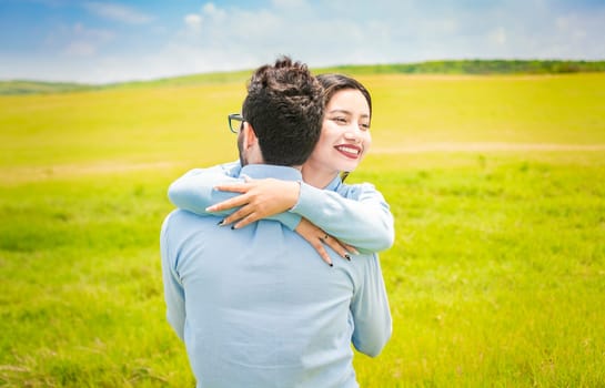 Close up of a happy couple hugging in the field, a young couple in love hugging in the green field, A man hugging his woman in a beautiful field