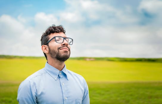 A young person breathing fresh air in the field, Man breathing fresh air in the field, Happy guy breathing fresh air in the grass