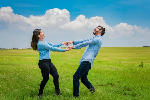 Happy couple spinning in a circle in the field, happy young couple spinning and playing in the field, young couple spinning in the field