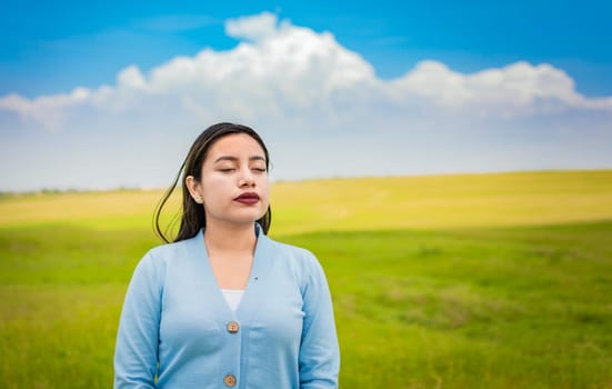 A young girl breathing fresh air in the field, Young woman breathing fresh air in the field in the morning, A young woman breathing deeply in the field