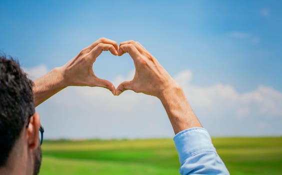 Hands together in the shape of a heart, man's hands together in the shape of a heart, hands forming a heart in the field, concept of person creating a heart with their hands