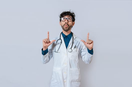 Surprised doctor pointing up. Amazed doctor pointing a promo up. Male doctor looking and pointing up isolated
