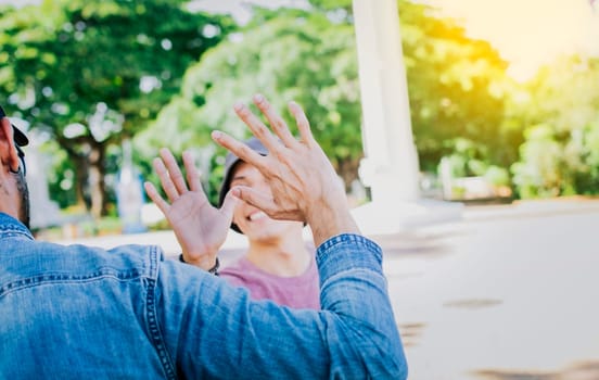 Close up of smiling people shaking hands in a park. Concept of two friends greeting each other with a handshake on the street, Back view of two smiling friends shaking hands on the street