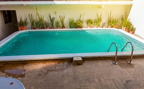 Crystal clear home swimming pool on a sunny day, Concept of home swimming pool designs. Beautiful home swimming pool with crystal clear waters