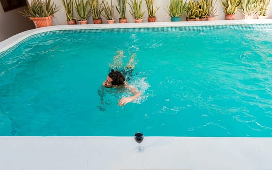 Young man swimming in a tropical hotel pool. Handsome man on vacation swimming in a hotel pool, Man on vacation swimming in a blue swimming pool