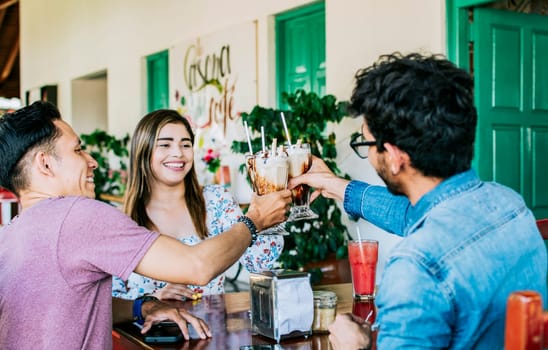 Happy friends enjoying a milkshake in a coffee shop. Three happy best friends meeting and toasting in a coffee shop, Happy young friends toasting in a coffee shop