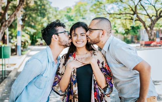 Two men kissing a girl cheek. Portrait of two guys kissing a girl cheek. Two young men kissing a woman cheek outdoor, love triangle concept. Polygamy concept