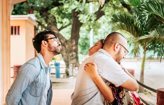 Unfaithful girlfriend hugging her boyfriend outdoors and secretly kissing another man, Unfaithful woman hugging her boyfriend and secretly kissing another man. Concept of infidelity and betrayal