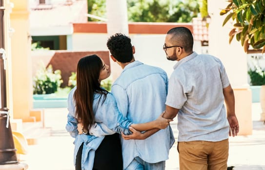 Woman holding hands with another man while walking with her boyfriend on the street. Love triangle concept. Unfaithful girl walking outdoor with her boyfriend while holding another man's hand