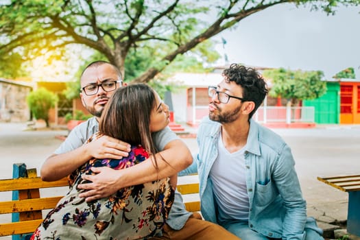 Unfaithful girlfriend hugging her boyfriend in a park secretly kissing another man. Couple infidelity concept, Unfaithful woman sitting hugging her boyfriend and secretly kissing another man.