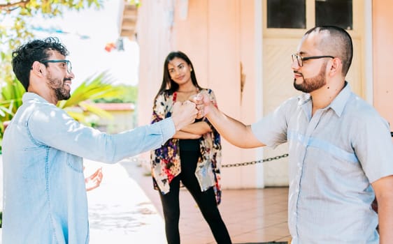 Two teenage friends bumping their fists outdoors. Concept of friends bumping fists amicably, Two overjoyed male friends bumping fists amicably on the street