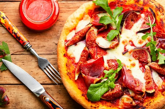 Appetizing pizza with bacon and autumn fruit, figs.