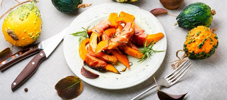 Autumn baked pumpkin pieces wrapped in bacon. Thanksgiving Day
