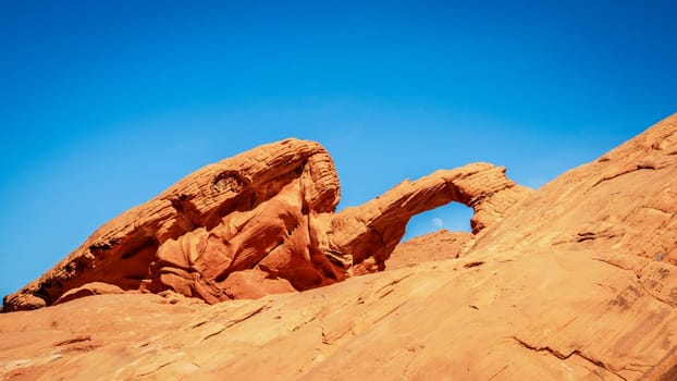 Moon rising over Arch Rock formation in Valley of Fire State Park in Nevada