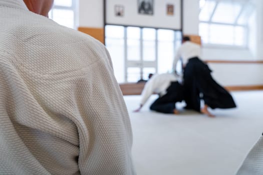 People practicing aikido martial art in a dojo background. Seiza position.