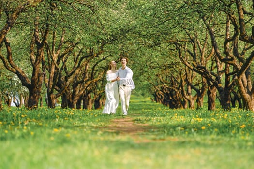 Happy newlyweds in white clothes hold hands of each other and dancing in the park
