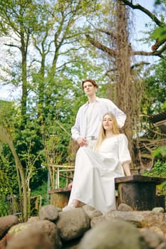 Happy couple posing outdoor among trees and rocks, low angle view