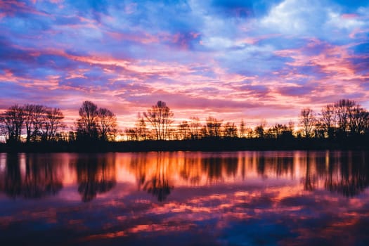 Nightscape photo at Adour French river in blazing red sunset with dramatic clouds floating. Real photography