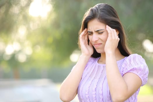 Woman suffering migraine walking in a park