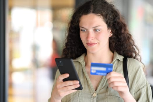 Woman buying online with credit card walling in the street