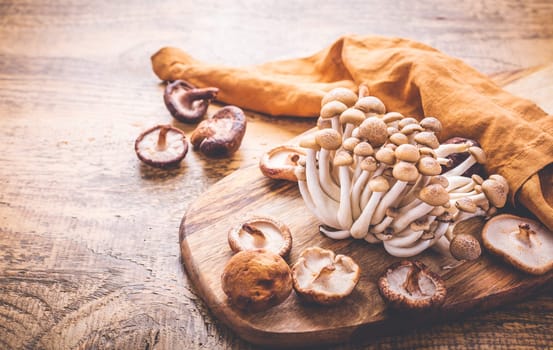 Raw brown shimeji mushrooms and shiitake on cutting board, edible mushrooms