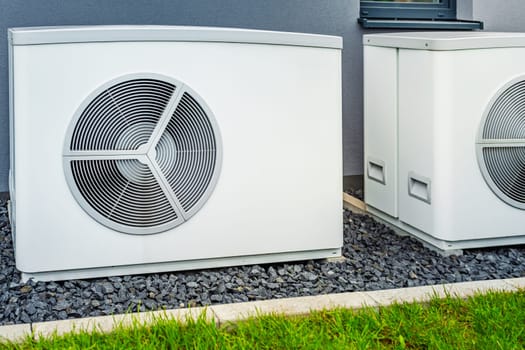 Two air source heat pumps installed outside of new and modern city house, green renewable energy concept of heat pump
