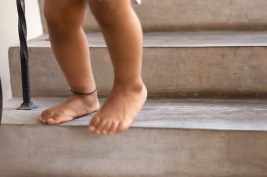 Feet of a one year old baby standing on the stair.