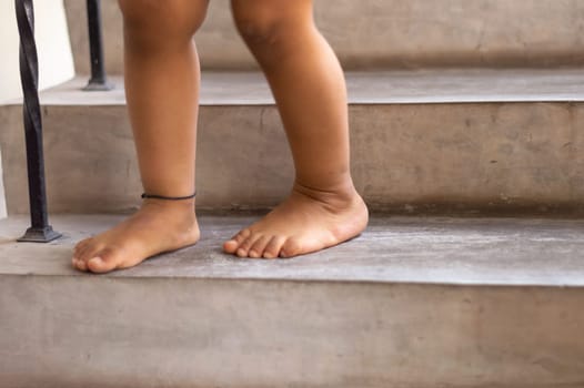 Feet of a one year old baby standing on the stair.