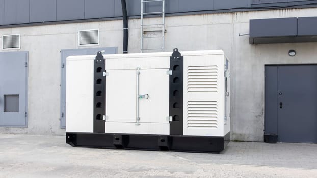 White auxiliary diesel generator for emergency power supply. Industrial generator connected to the control panel by a cable wire. Backup power supply of the generator