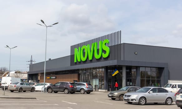 Ukrainian supermarket chain Novus. Green large signboard of the shopping center outside, on the street. Signboard against the sky. The building of the supermarket. Ukraine, Kyiv - May 01, 2023