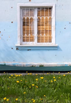 The buildings were hit by shelling. Boarded up windows and damaged facade. Preparing the house for hostilities and war. Destroyed houses in the city during the war in Ukraine