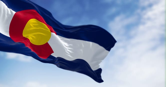 Colorado state flag waving in the wind on a clear day. Three blue, white, and blue stripes. Red C with gold disk on top. 3D illustration render. Fluttering fabric. Selective focus
