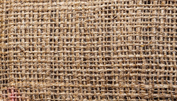 Natural textured background of intertwined threads. Macro photo of the texture of old burlap. Light brown abstract background.