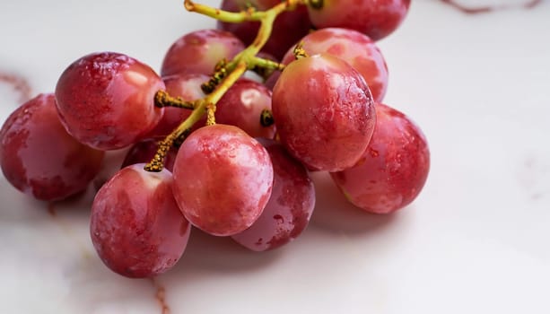 Bunch of grapes and scatter on pink background. Variety - Red Globe with large, seeded red grapes. Isolated high quality photo