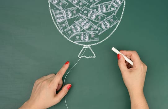 Chalk-drawn balloon with drawn dollars and female hands, concept of inflation