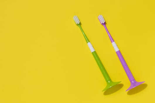 Two plastic toothbrushes on a yellow background, oral hygiene