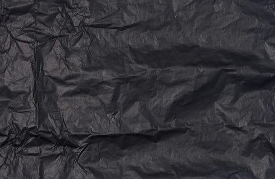Crumpled sheet of black parchment paper, abstract background
