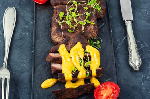 Roasted ostrich meat steaks with sauce. African cuisine. Copy space