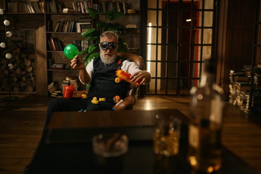 Selective focus of rich elegant senior businessman playing toys at home office. Elderly mature male character wearing elegant suit and pilot goggles having fun and rest after hard work day