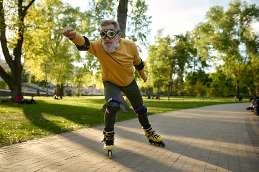 Funny mature man wearing goggles riding fast on roller skates in city street
