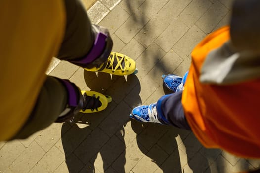 Cropped top view shot of man and boy legs wearing rollerblades over city park background. Active recreation time and sports activity in summer