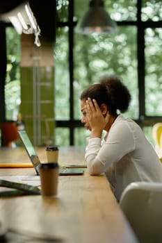 Shocked worried business woman holding head looking at laptop computer sitting at table in office room. Trouble on work, bad email notification or online project failure concept