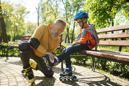 Father helping son to put on roller skates. Happy family active rest and leisure recreation time in urban park on weekend
